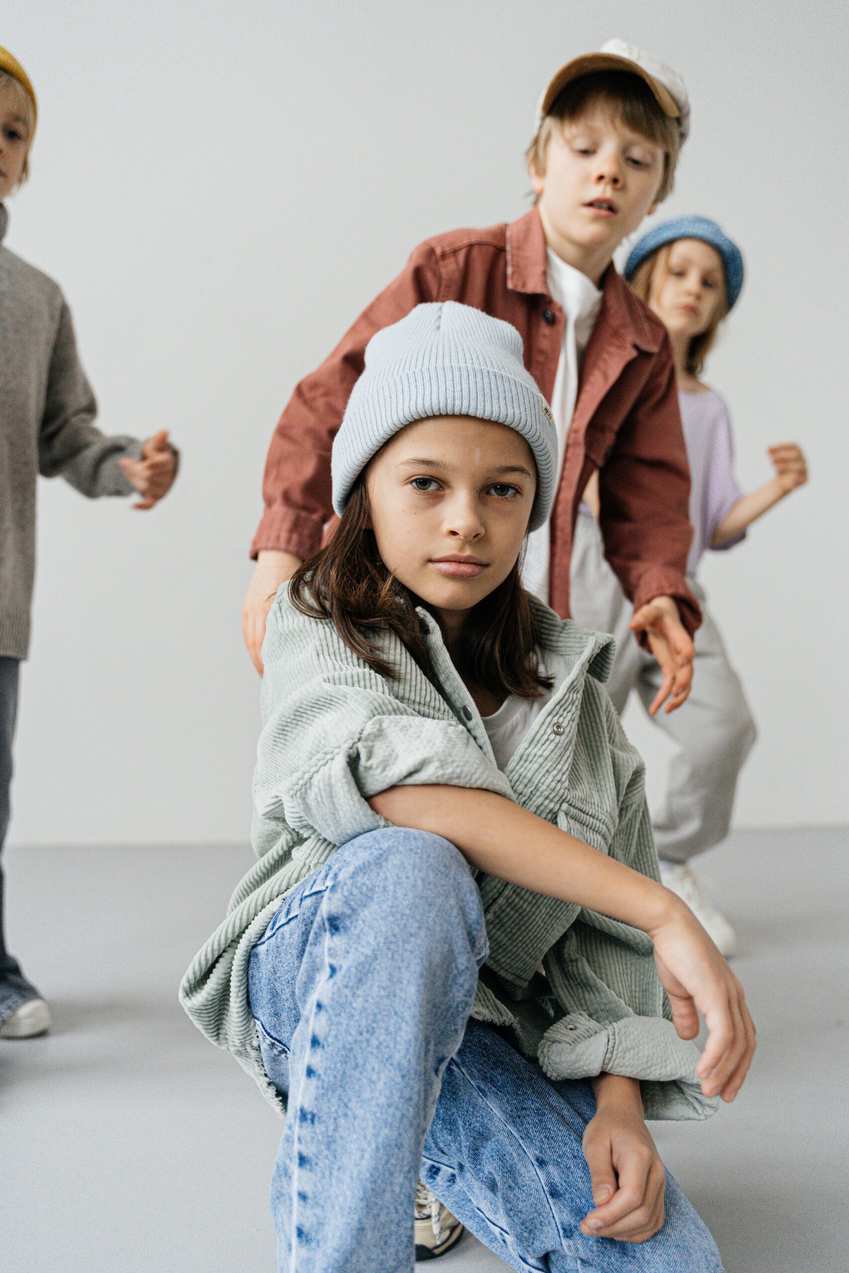 pexels photo 6261908 6261908 Four children in fashionable jackets and caps posing creatively against a white background.